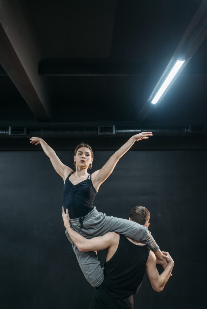 Dancer being lifted mid-performance on a dark stage