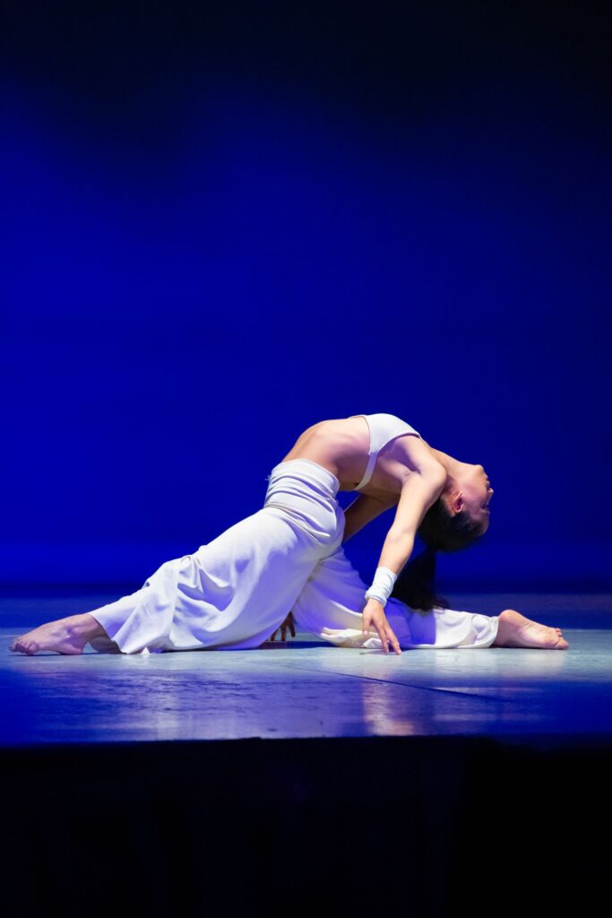Dancer in elegant pose against a blue backdrop