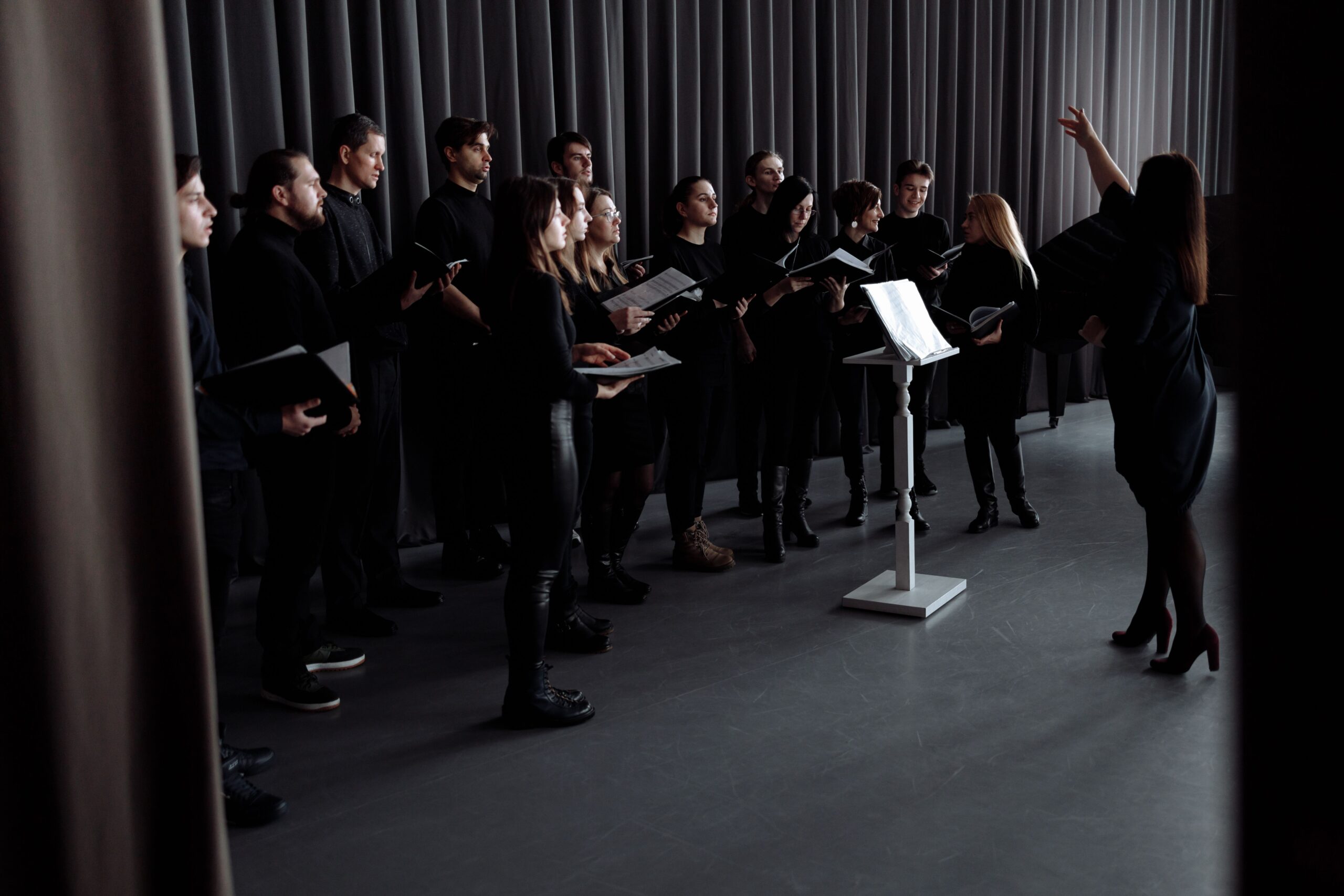 Choir ensemble singing together under dramatic stage lighting